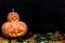 Glowing pumpkins one on another. Pumpkins in leaves on a dark wo