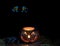 Glowing scary pumpkin decoration in darkness with owl eyes in ba