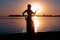 Glowing silhouette of slim woman stay in dance pose near big river