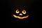 Glowing smiling face Halloween pumpkin, candle holder, isolated on night dark black background.