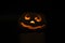 Glowing smiling face Halloween pumpkin, candle holder, isolated on night dark black background.