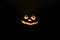 Glowing smiling face Halloween pumpkin, candle holder, isolated on night dark black background.