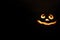 glowing smiling face Halloween pumpkin, candle holder, isolated on night dark black background. space for text.