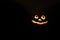 glowing smiling face Halloween pumpkin, candle holder, isolated on night dark black background. space for text.