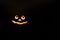 Glowing smiling face Halloween pumpkin, candle holder, isolated on night dark black background. space for text.