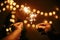 Glowing sparklers in hands on background of golden christmas tree lights, couple celebrating in dark festive room. Happy New Year