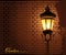 Glowing street lamp against a brick wall