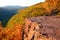 Glowing sunlight strikes a rock outcrop and fall foliage