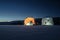 Glowing tents on the ice of a frozen lake. Night landscape of winter fishing