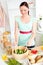 Glowing young woman preparing salad at home