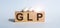 GLP abbreviation stands for Good Laboratory Practice on wood background