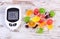 Glucometer with bad result of measurement sugar level and colorful candies, reduction eating sweets concept