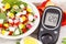 Glucometer for checking sugar level and fresh salad with eggs and vegetables, diabetes and healthy nutrition concept