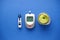 Glucometer, lancet pen, centimeter and fruits on blue background close-up, flat lay. Diabetes concept