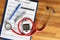 Glucometer with stethoscope lying on glucose control document closeup