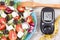 Glucometer with sugar level, centimeter and greek salad with feta cheese and vegetables. Best food for diabetics, dieting and