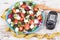 Glucometer with sugar level, centimeter and greek salad with feta cheese and vegetables. Best food for diabetics, dieting and