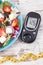 Glucometer with sugar level and greek salad with feta cheese and vegetables. Best food for diabetics, dieting and slimming