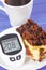 Glucose meter with high and bad result sugar level and fresh baked homemade cheesecake with coffee. Dieting during diabetes