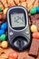 Glucose meter with result of sugar level and candies with cookies. Diabetes and reduction of eating sweets