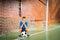 Glum young boy sitting waiting in the goalposts