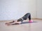 Gluteal bridge on pink small fitness ball. Young caucasian woman doing pilates with special equipment in fitness studio.