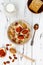 Gluten free amaranth and quinoa porridge breakfast bowl with figs, caramelized almonds, raisins and honey over rustic white table.