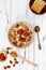 Gluten free amaranth and quinoa porridge breakfast bowl with figs, caramelized almonds, raisins and honey over rustic white table.