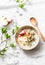 Gluten free breakfast - quinoa, coconut milk, banana, apple, peanut butter bowl on light background, top view. Delicious diet, veg