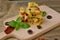 Gluten free meal from roasted corn flour, dried tomato, black olives and basil on wood on gunny cloth on brown wooden background