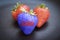 GMO genetically modified strawberry against organic on the dark background