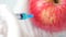 GMO injection with syringe in apple by the hands in white gloves