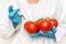 GMO scientist injecting liquid from syringe into red tomatoes