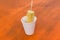 A gnawed cob of freshly boiled corn in a paper cup on the table