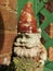 Gnome in Close Up Standing on a Shelf With Green Trellis Background