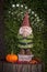 Gnome with pumpkin on tree stump with fairies and word Gnomaste