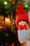 Gnome toy as winter holidays decoration against unfocused new year`s tree with burning festive garland lights.