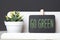 GO green on blackboard and green plant in white pot on table and dark grey wall in office desk.eco office