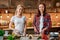 Go green, have a vegetable. Smiling young women cutting vegetables in modern kitchen. Cozy interior.