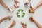 Go green with recycling. Top view of many hands holding different waste, garbage types with recycling sign made of paper