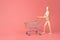 Go shopping concept. Photo of wooden mannequin pushing card on wheels isolated pastel light color backdrop