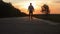 Go to the sunset, the lower angle. Young man walking on a countryside road against the sunset.