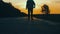 Go to the sunset, the lower angle. Young man walking on a countryside road against the sunset.