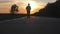 Go to the sunset, the lower angle. Young man walking on a countryside road against the sunset.