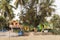 GOA, INDIA - MARCH 17, 2019: Bright colored tourist bungalows under palm trees on the sandy shore of the Indian ocean