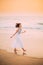 Goa, India. Young Caucasian Woman With Fluttering Hair In Wind In White Dress Walking Along Seashore, Enjoying Life And