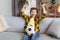 Goal. Happy little boy sport supporter watching match on tv with soccer ball and celebrating victory at home, free space