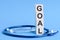 GOAL word written on wooden blocks and stethoscope on light blue background