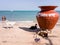 Goats and dogs resting beside a large earthern pot on a white sand beach in the