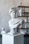 God Apollo bust sculpture. Ancient Greek god of Sun and Poetry Plaster copy of a marble statue on grange concrete wall background.